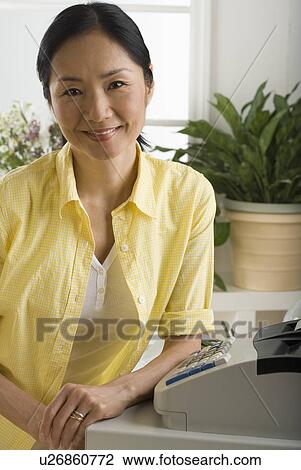 Asian woman smiling and leaning on cash register View Large Photo Image Stock Image - Asian woman smiling and leaning on cash register. Fotosearch