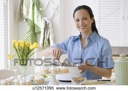 Stock Photography - Asian woman stirring batter in kitchen. Fotosearch