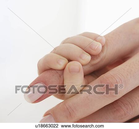 Stock Image - Baby holding mother’s finger. Fotosearch