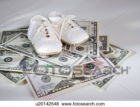 Baby shoes on stack of US Dollars View Large Photo Image Stock Photo - Baby shoes on stack of US Dollars. Fotosearch