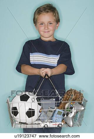 Boy holding shopping basket with toys View Large Photo Image Stock Photo - Boy holding shopping basket with toys. Fotosearch