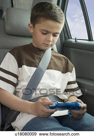 Boy playing video game in car View Large Photo Image Stock Photo - Boy playing video game in car. Fotosearch