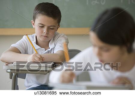 Boy writing at desk in classroom View Large Photo Image Stock Photography - Boy writing at desk in classroom. Fotosearch