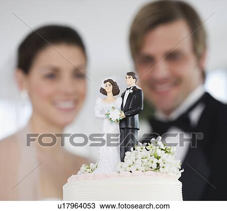 Stock Image - Bride and groom smiling at wedding cake. Fotosearch