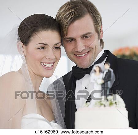 Bride and groom smiling at wedding cake View Large Photo Image Stock Photo - Bride and groom smiling at wedding cake. Fotosearch