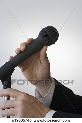 Stock Photography - Businessman adjusting microphone. Fotosearch