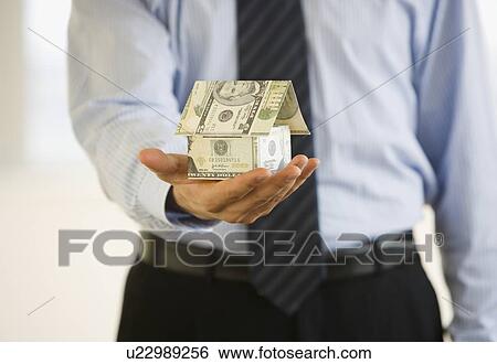 Businessman holding house made money View Large Photo Image Stock Photograph - Businessman holding house made money. Fotosearch