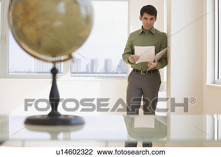 Businessman holding paperwork in doorway View Large Photo Image Stock Image - Businessman holding paperwork in doorway. Fotosearch