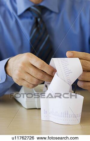 Businessman looking at adding machine tape View Large Photo Image Stock Photograph - Businessman looking at adding machine tape. Fotosearch