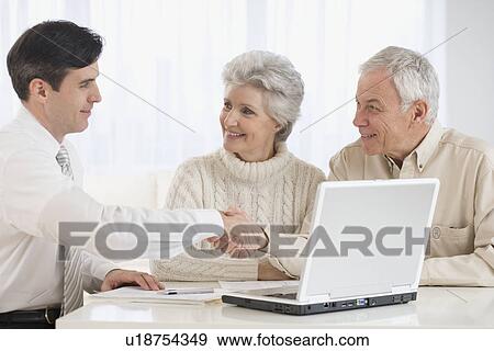 Businessman shaking hands with senior couple in home View Large Photo Image Stock Photo - Businessman shaking hands with senior couple in home. Fotosearch