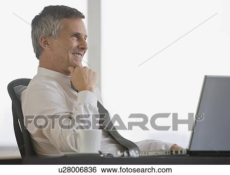 Businessman sitting at desk View Large Photo Image Stock Photograph - Businessman sitting at desk. Fotosearch