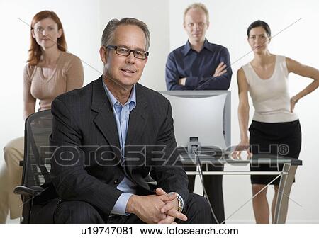 Stock Image - Businessman smiling with coworkers in background. Fotosearch