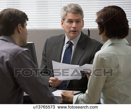 Businessman talking to couple in office View Large Photo Image Stock Image - Businessman talking to couple in office. Fotosearch