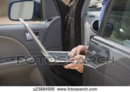 Businessman using laptop in car View Large Photo Image Stock Photograph - Businessman using laptop in car. Fotosearch