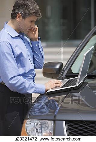 Businessman using laptop on car View Large Photo Image Stock Image - Businessman using laptop on car . Fotosearch