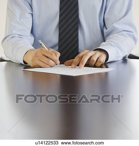 Stock Image - Businessman writing at table. Fotosearch