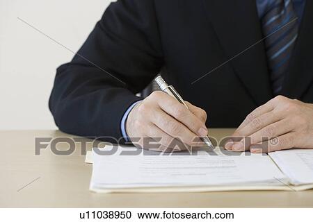 Stock Image - Businessman writing in folder. Fotosearch