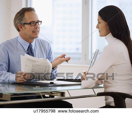 Businesspeople discussing paperwork View Large Photo Image Stock Photo - Businesspeople discussing paperwork. Fotosearch