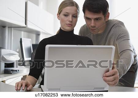 Stock Image - Businesspeople looking at laptop. Fotosearch