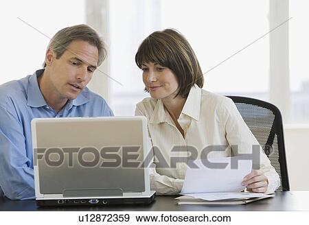Businesspeople looking at laptop View Large Photo Image Stock Photo - Businesspeople looking at laptop. Fotosearch