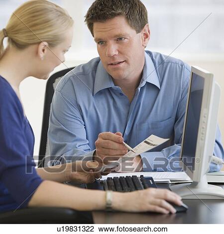 Stock Image - Businesspeople looking at paperwork. Fotosearch