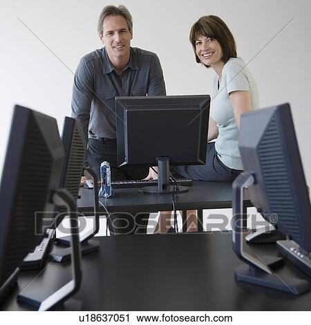 Stock Image - Businesspeople next to computer. Fotosearch