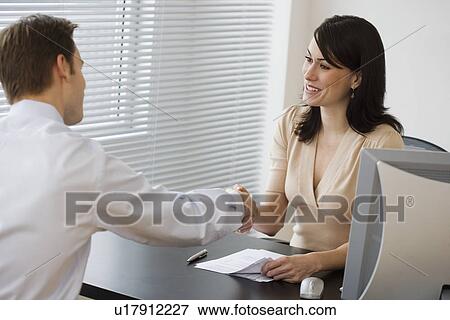 Stock Photo - Businesspeople shaking hands over desk. Fotosearch