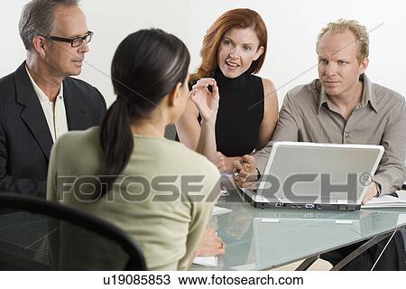 Businesspeople talking around laptop View Large Photo Image Stock Image - Businesspeople talking around laptop. Fotosearch