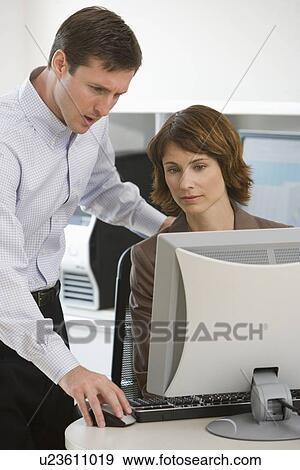 Stock Photo - Businesswoman and businessman looking at computer. Fotosearch