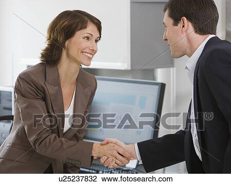 Stock Image - Businesswoman and businessman shaking hands. Fotosearch