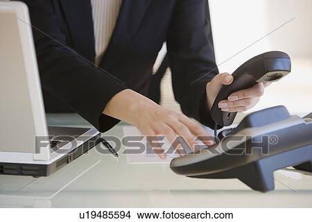 Picture - Businesswoman answering telephone. Fotosearch