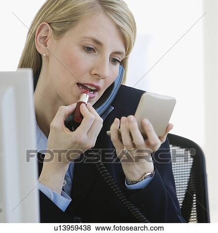 Businesswoman applying lipstick View Large Photo Image Stock Photo - Businesswoman applying lipstick. Fotosearch