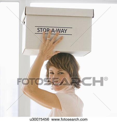 Businesswoman carrying storage box on head View Large Photo Image Stock Photograph - Businesswoman carrying storage box on head. Fotosearch