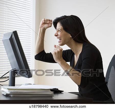 Stock Image - Businesswoman cheering at computer. Fotosearch