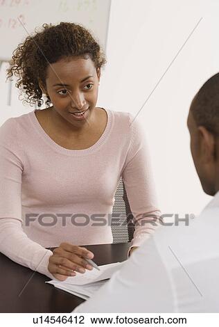 Businesswoman discussing paperwork with coworker View Large Photo Image Stock Image - Businesswoman discussing paperwork with coworker. Fotosearch