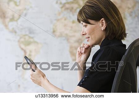 Stock Photograph - Businesswoman looking at electronic organizer. Fotosearch
