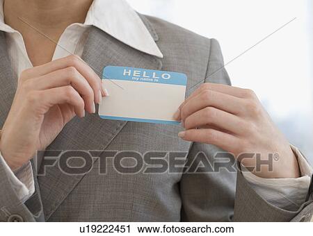 Stock Image - Businesswoman putting on Hello My Name Is sticker. Fotosearch