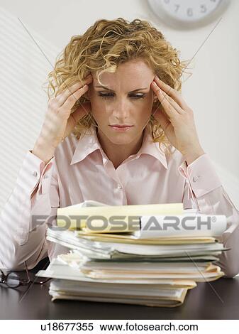 Businesswoman rubbing temples and looking at paperwork View Large Photo Image Stock Photography - Businesswoman rubbing temples and looking at paperwork. Fotosearch
