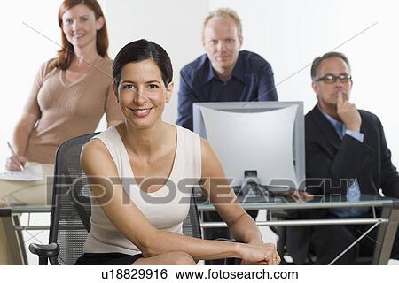 Stock Photograph - Businesswoman smiling with coworkers in background. Fotosearch