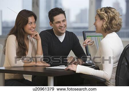 Businesswoman talking to multi-ethnic couple View Large Photo Image Stock Photo - Businesswoman talking to multi-ethnic couple. Fotosearch