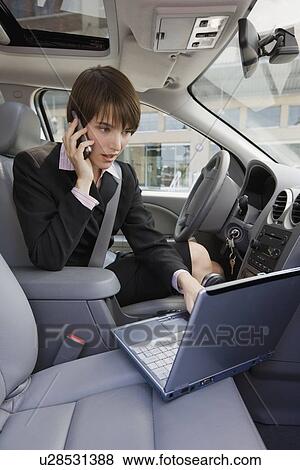 Stock Photo - Businesswoman typing on laptop in car. Fotosearch