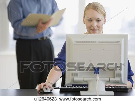 Stock Image - Businesswoman using computer at desk. Fotosearch