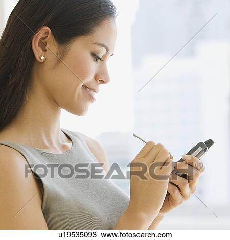 Stock Image - Businesswoman using electronic organizer. Fotosearch