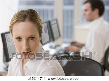 Stock Image - Businesswoman with co-worker in background. Fotosearch