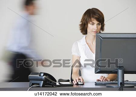 Stock Image - Businesswoman working at desk. Fotosearch