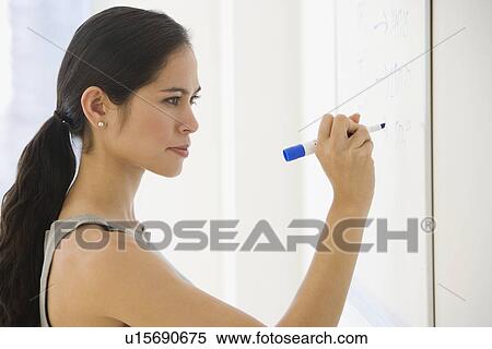 Stock Photography - Businesswoman writing on dry erase board. Fotosearch
