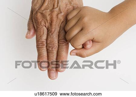 Stock Photo - Close up of child's hand holding pinky finger on senior's hand. Fotosearch