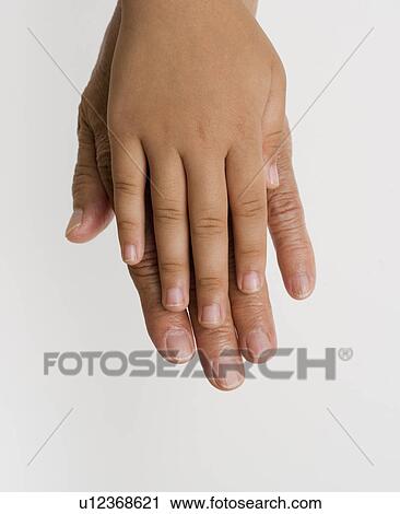 Stock Image - Close up of child's hand laying on adult's hand. Fotosearch