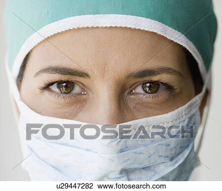 Stock Image - Close up of female doctor wearing surgical mask. Fotosearch