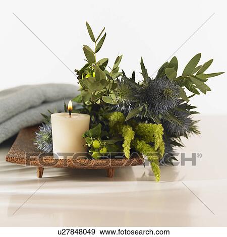 Close up of lit candle and plants on tray next to towel View Large Photo Image Stock Photo - Close up of lit candle and plants on tray next to towel. Fotosearch